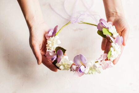 Woman's hands hold foam wreath with sprint flowers. Fashion accessorise for hairstyleの写真素材