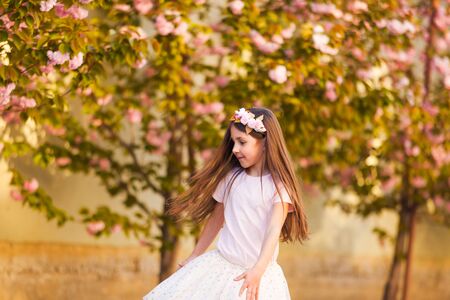 Spring portrait, adorable little girl dance near sakura treeの写真素材