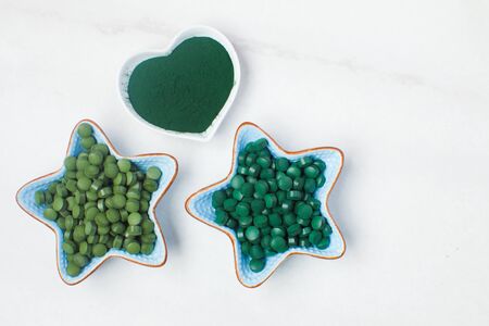 Spirulina algae powder and tablets on white marble background from top viewの写真素材