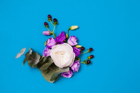 Flat lay of white rose and violet eustoma with copy space on blueの写真素材