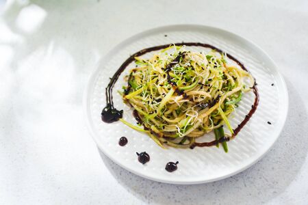 Raw zucchini noodles in on the plate close up