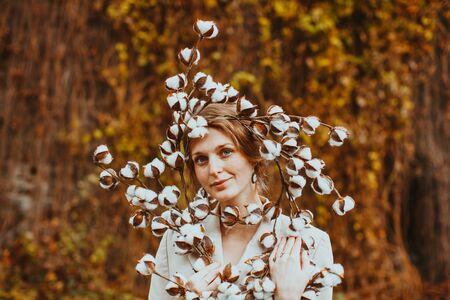 Autumn portrait sensual young woman. Girl holding beautiful cotton flowersの写真素材