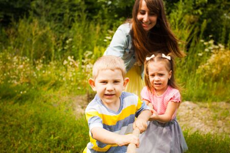 Happy mother and kids playing tug of war in parkの写真素材