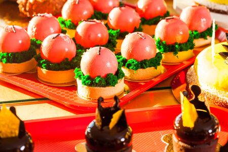 Luxury european desserts which look like red apples. Mousse portion cake covered with red glaze....