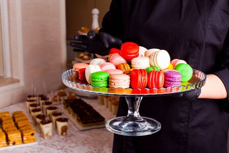 Colorful macaroons and other desserts served on the table. Catering service.