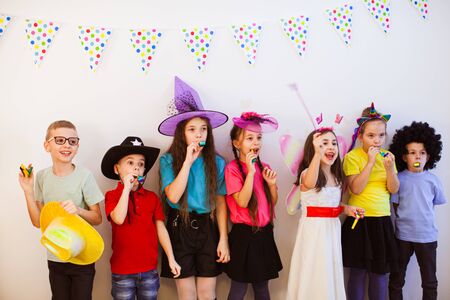 Large group of kids in funny hats on a birthday party blowing a whistles. Happiness and friendship.の写真素材