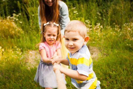 Young family playing tug of war on nature