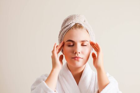 Beautiful young woman with clean perfect skin doing facial self- massage at homeの写真素材