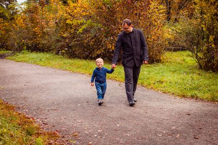 Dad and son in the autumn parkの写真素材