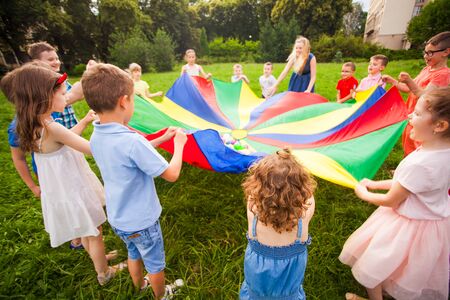 Happy kids holding parachute during funny game