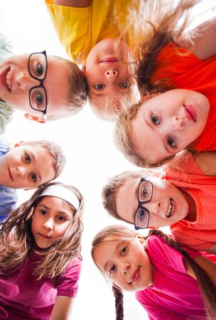 Cute boys and pretty girls looking at camera, view from down. Team of kids outdoors.の写真素材