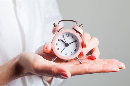 Silhouette of a woman holding an alarm clock in pink. Time management concept