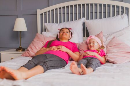 Mother and little daughter laying on bed