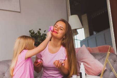 Mother enjoying beauty procedures made by her daughterの写真素材