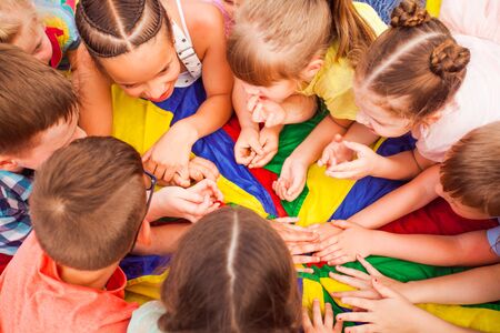 Top view children heads in a circle. Cheerful kids laying closely in a circle, discussing something. Friends creating new game and discussing rules. Agreement skills conceptの写真素材