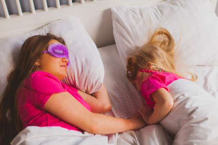 Young mom and cute little girl are sleeping in cozy bedroomの写真素材