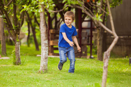 The child is running along the lawn between a trees