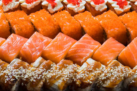 Macro shot of a set of sushi rolls with different ingredients. Sushi is laid out in a row forming a beautiful patternの写真素材