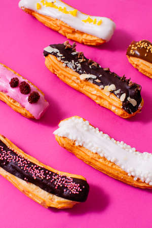 Wonderful eclairs isolated on the pink background with different fillings: chocolate, caramel, vanilla, strawberry, raspberry lemonの写真素材