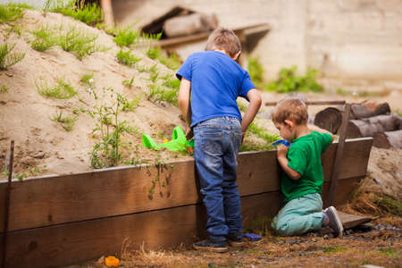 View from the back of two little boys playing in the sandbox at a construction siteの写真素材