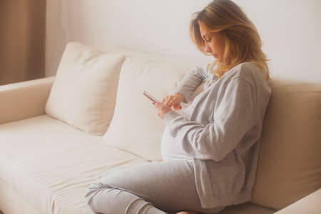 Pregnant woman counting contractions using smartphone appの写真素材