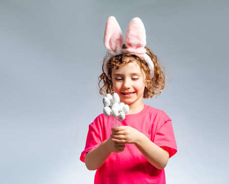 the adorable little girl with pink bunny ears counts eggs