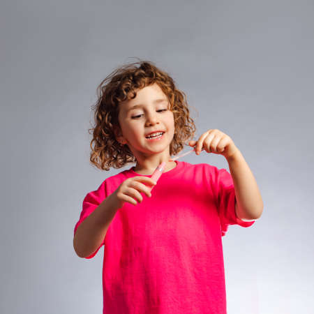 the little girl with makeup uses lip gloss
