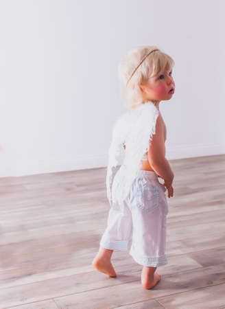 the cute baby is wearing a cupid costume in the roomの写真素材