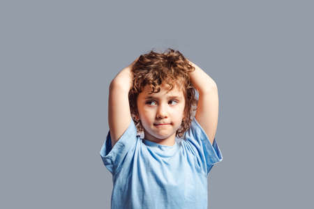 Little girl stand and thinking on a gray background