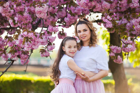 mom and daughter are standing next to a tender plantの写真素材