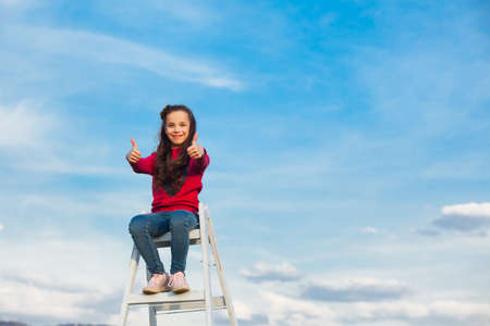 the girl on top of a ladder against the skyの写真素材