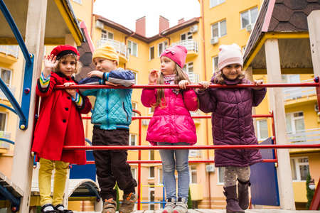 the smiling kids are standing together on the playground equipmentの写真素材