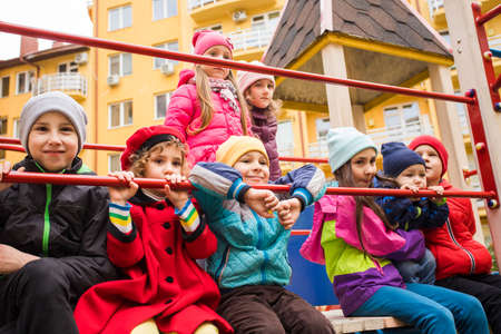 the smiling kids are standing together on the playground equipmentの写真素材