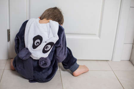 the upset kid is sitting on the floor in a closed positionの写真素材