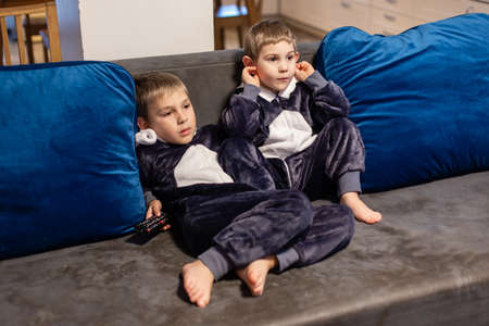 the little brothers in kigurumi watching tv at homeの写真素材