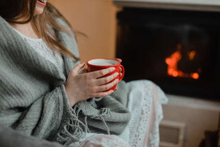 the woman with hot drink relaxes by the fireplaceの写真素材