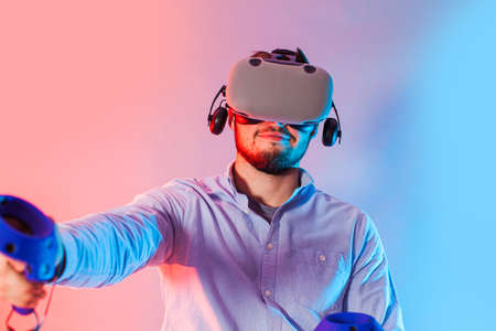 Young man using the virtual reality glasses and two gamepad