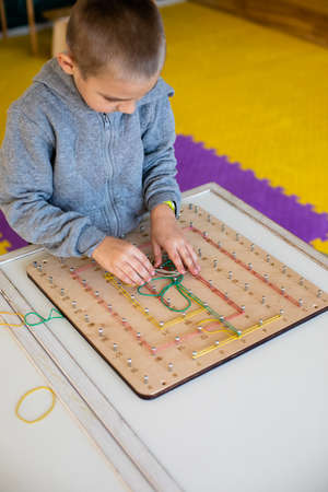 Lovely preschool boy exploring geoboard at daycare. Montessori games for kids development.の写真素材