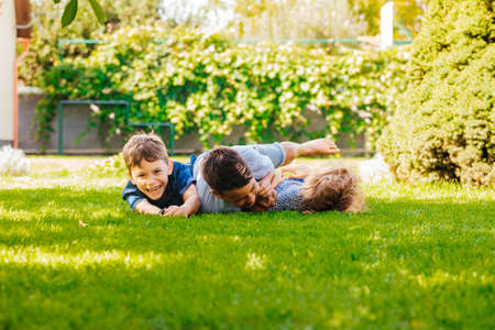 Portrait of three little children lying on a green grass