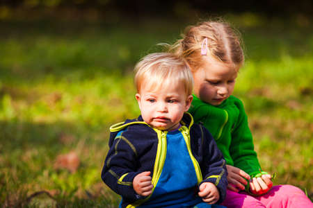 The cheerful girl is hugging her crying brother outdoor