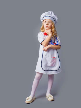 Little girl in costume of doctor profession isolated on greyの写真素材