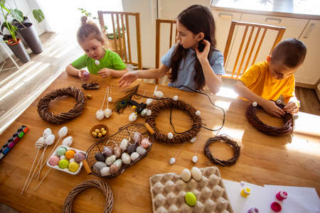 Cheerful kids creating Easter decorations at home