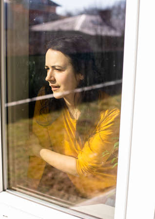 the young woman is looking through the window on sunny dayの写真素材