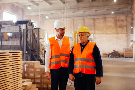Young engineer and elderly worker inspect productionの写真素材
