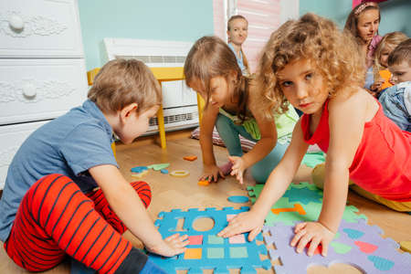 Cute children playing with soft puzzles sitting on a floorの写真素材