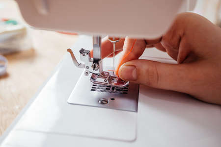 Closeup hands inserting thread into sewing machine needleの写真素材