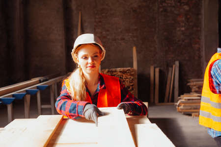 Attractive woman woodwork factory worker holding wooden plankの写真素材