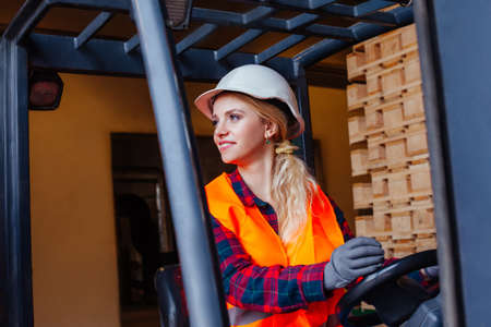 Smiling woman driving forklift truck at the warehouseの写真素材