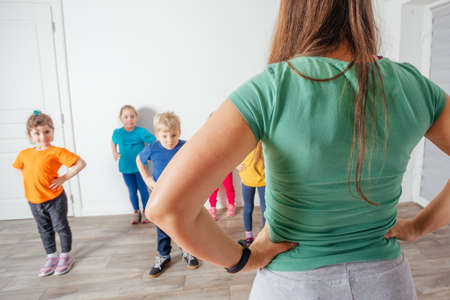 Teacher engaging prescholers to do morning physical exercises