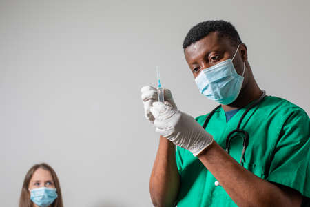 Doctor in medical mask holding syringe with medicationの写真素材